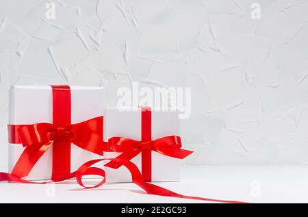 White different size gift boxes with red silk ribbon in white interior, copy space, wedding background. Stock Photo
