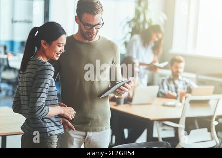 Two ambitious young people using tablet in coworking space Stock Photo