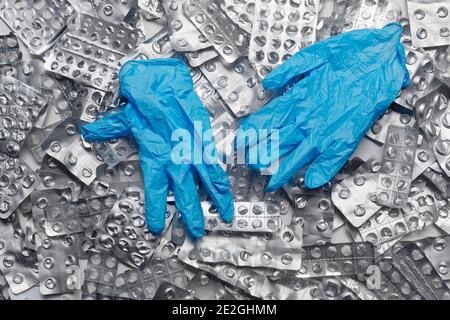 Protective rubber gloves on pile of blister packs Stock Photo