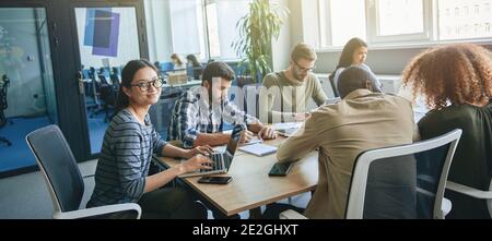 Hard-working team of young office workers working at desk Stock Photo