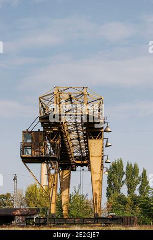 Old rusty industrial overhead crane also known as gantry or bridge crane at a railway station in Bulgaria Stock Photo