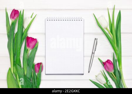 Open blank notebook, pen with tulip flowers. Top view, flat lay. Abstract feminine concept. Spring mockup background Stock Photo