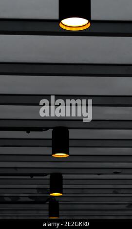 Black steel lamps lit with yellow light and hung in a hallway. Stock Photo