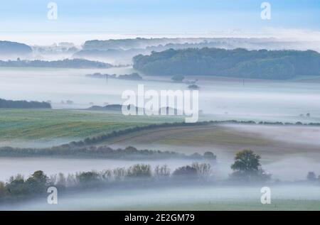 Dramatic viewpoint of the Kent Downs AONB on a misty morning; taken from the Folkestone Downs with Dungeness Power Station in the distance. Stock Photo