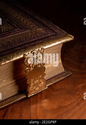 A leather bound antique book with a decorative metal clasp photographed on a glossy wooden surface Stock Photo