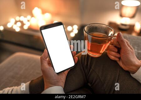 New reading technology using smartphone to enjoying preferred ebook: close up of unrecognizable woman sitting on sofa holding a cup of tea in one hand Stock Photo
