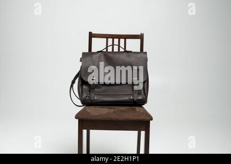 Brown men's shoulder leather bag for a documents and laptop on a brown chair with a white background. Mens leather brief case, messenger bags, leather Stock Photo