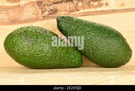 Two whole green dietary ripe avocados, on a background of natural wood. Stock Photo