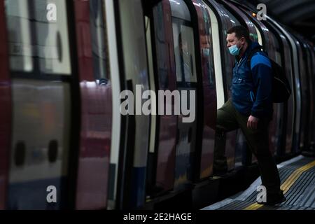 A man in a face mask boards an underground train in London during England's third national lockdown to curb the spread of coronavirus. Stock Photo