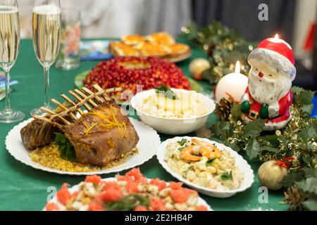 A festive table with many delicious dishes. Lamb rack, two glasses of champagne, salads and snacks on the festive table. Celebrations at home. Stock Photo