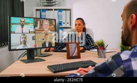 Paralysed freelancer in wheelchair having videomeeting discussing online with remotely colleagues in business office. Handicapped businessman working in financial company using modern technology. Stock Photo