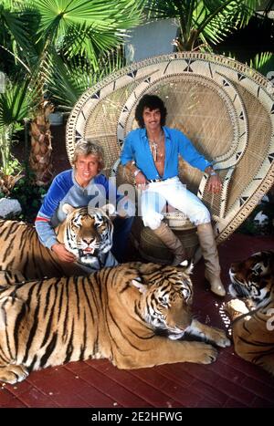 FILED - 30 November 1980, US, Las Vegas: German-born American magicians and tamers Siegfried Fischbacher (l) and Uwe Horn, aka Roy (r), sit with their tigers on their estate. The 'Siegfried & Roy' magician Siegfried Fischbacher is dead. The Rosenheim native died on Jan. 13, 2021, at the age of 81, his sister confirmed to the German Press Agency on Jan. 14. Photo: Horst Ossinger/dpa Stock Photo