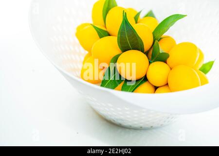 Close up fruit in basket, beautiful Marian Plum bunch or Plum Mango bunch in modern plastic white basket, tropical Thailand fruit, sweet and sour Asia Stock Photo