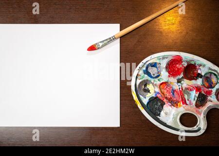 Paint brush laying on white black paper on wooden table. Copy space for text. Stock Photo