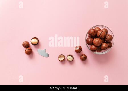 Raw macadamia nut scattered on a pink solid background with copy space. Minimal composition. Stock Photo