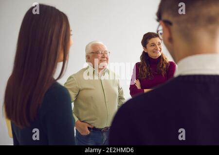 Happy people of different ages talking in group therapy session or community club meeting Stock Photo