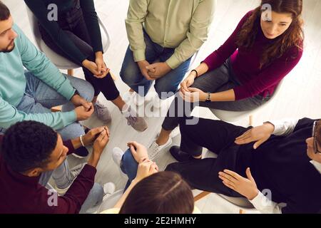 Diverse people sitting in circle listening to man sharing his problems in group therapy session Stock Photo