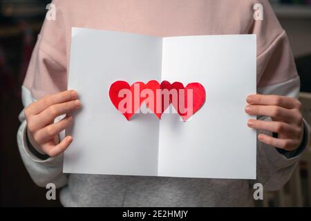 Hand golding handmade greeting card for Valentines day. I love you sign painted with red paint on white paper. Stock Photo