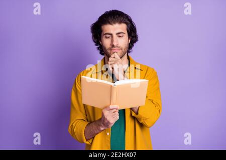 Photo of young brown hair man red book serious focused hand touch chin isolated over purple color background Stock Photo