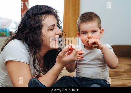 Boy eating  chocolate while playing with mom Stock Photo