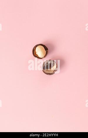 Organic Macadamia nuts on pink background, top view. Healthy snack Stock Photo