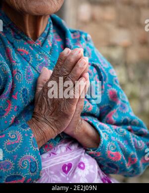 Unrecognized elder woman wearing blue cloths crossing her wrinkled hands. Aging age process Stock Photo