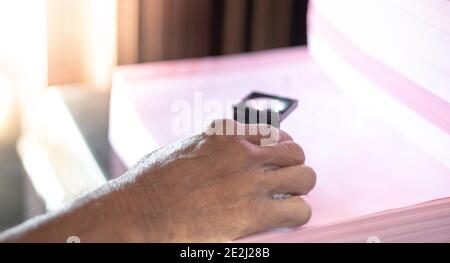Close up male hand worker in a printing and press centar uses a magnifying glass and check the print quality. Stock Photo
