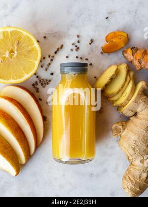 Healthy immune system boosting orange, apple and lemon ginger shot in a small glas bottle Stock Photo