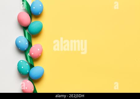 Easter colorful eggs are arranged in a row on a yellow and gray background. Greeting card with copy space. Stock Photo