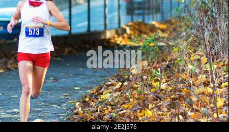 Side view of female teen athlete in sports bra and tights successfully  finishing race on track at stadium Stock Photo