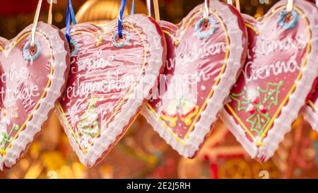 Christmas gingerbreads are hanging on ribbons. Sweet delicious gingerbread cookies in the form of hearts.Tasty homemade Christmas cookies on color bac Stock Photo