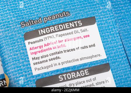 Close-up shot of food ingredients on plastic wrapper of ASDA salted peanuts bag. Food peanut allergy warning on plastic packaging, ingredient list. Stock Photo