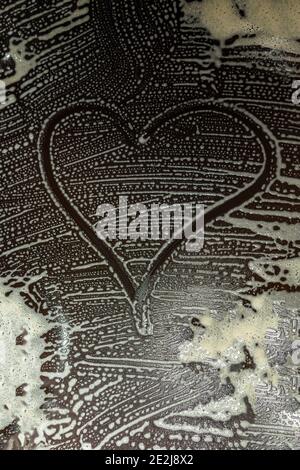 the heart sign painted on the soap stains from the foam. Cleaning the kitchen surface. Valentine's Day Stock Photo