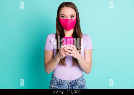 Photo portrait of surprised girl wearing facial fabric mask reading terrible news isolated on vivid teal color background Stock Photo