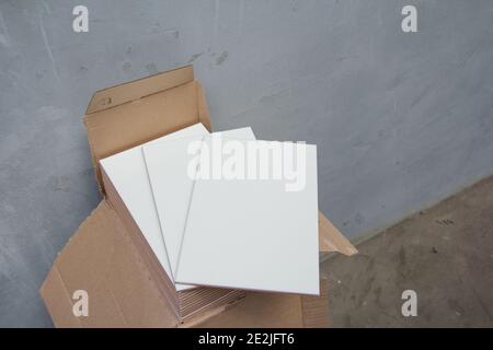 Laying Ceramic Tiles on the wall. White ceramic tiles. Renovation work. Material for repairing walls in a building. Stock Photo