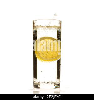 Lemon slice splashing into glass of water Stock Photo