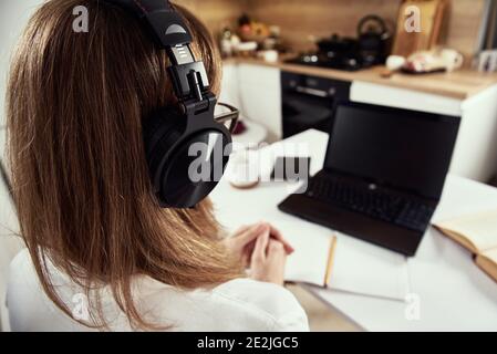 Remote work. Online cources, distance education and e-learning concept. Woman in headphones listen audio course at laptop Stock Photo