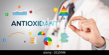 Nutritionist giving you a pill with ANTIOXIDANT inscription, healthy lifestyle concept Stock Photo