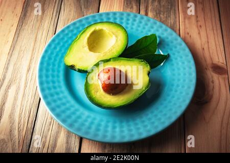 Fresh avocado fruit on a blue plate on wooden table. The concept of healthy eating. Food photography Stock Photo