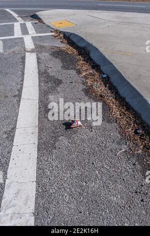 Discarded snack chips bag laying alongside the curb in the roadway along with other debris polluting the environment on a bright sunny day in winter Stock Photo