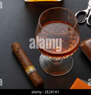 Athens Greece, December 30, 2020. Cohiba Cigar, cuban premium quality robusto. Tobacco and alcohol brandy or whiskey on black table, closeup view.  Sm Stock Photo