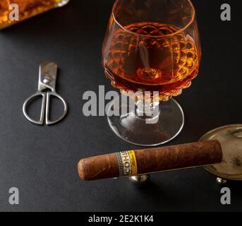 Athens Greece, December 30, 2020. Cohiba Cigar, cuban premium quality robusto and alcohol brandy or whiskey on black table, closeup view.  Smoking and Stock Photo