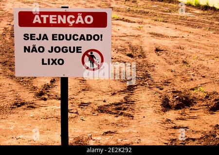 Sign (red, white and black colors) warning to not throw the garbage on the wasteland behind it: "Attention - Be Polite! Don't throw garbage" Stock Photo