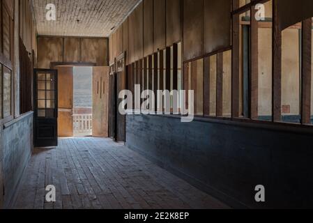 An empty hallway in a wooden building. The door at the end is open to the outside world. Stock Photo