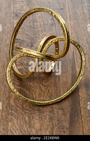 Gold metal torus infinity shape on dark hickory wood