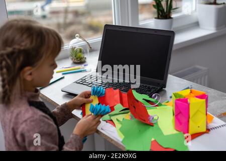 Portrait of pretty little girl smiling happily at camera while making handmade Christmas decorations during art and craft class of pre-school, copy Stock Photo
