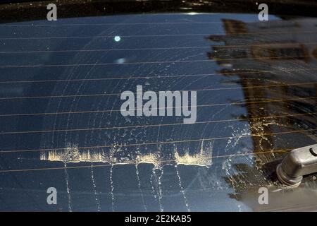 glass of a dirty car in stains of dirt and dust after cleaning by a car wiper close-up of the rear window. Stock Photo