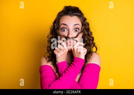 Photo portrait of goofy girl making hair mustache pouting holding with two hands wearing casual pink crop-top isolated on bright yellow colored Stock Photo