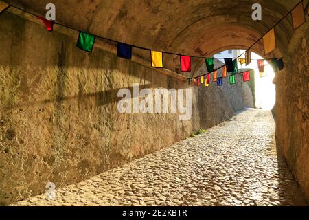 Tunnel through rock hung with flags. Stock Photo
