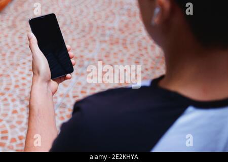 Over the shoulder shot of man holding and watching a mobile smart phone outdoors with a black touchscreen Stock Photo